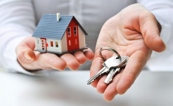 На руках человека модель дома и ключи